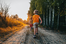 Cute kids, boys runs at summer nature road. Brothers, playing outdoors. Sunset. Happy childhood. High quality photo