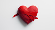 Bandaged red heart on white background.