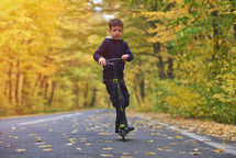 boy riding scooter, outdoor in autumn environment on sunset warm light