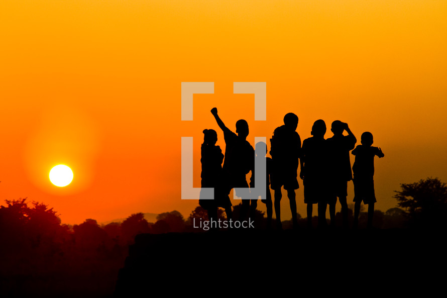 A group of children against a sunset.