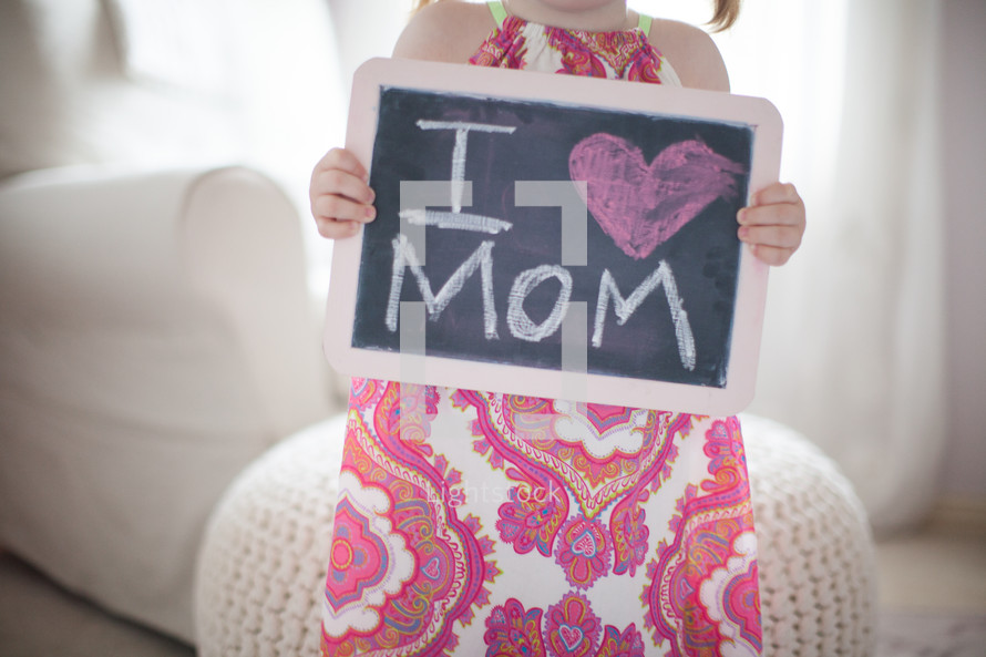a little girl holding a chalkboard sign that reads I heart mom 