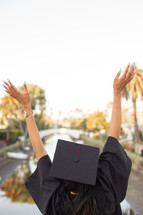 female African American graduate with raised hands 