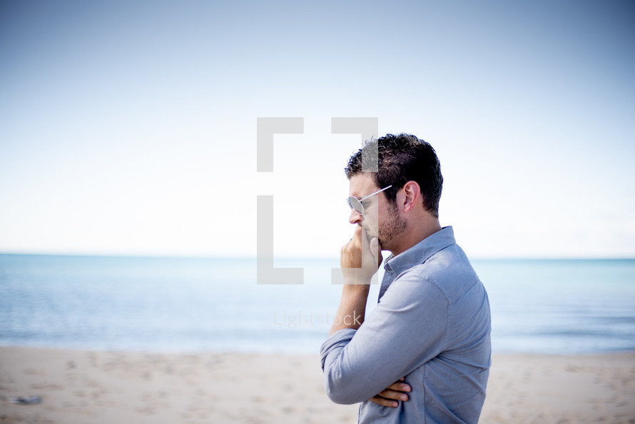 man standing on a beach thinking 