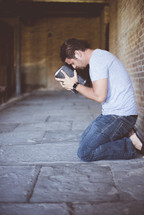 a man kneeling in prayer holding a Bible 