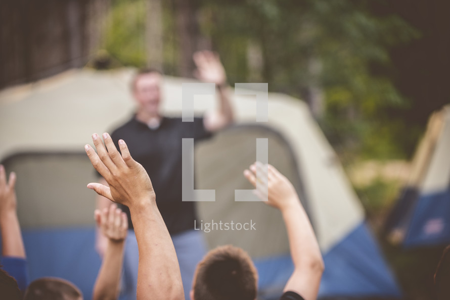 raised hands at a campsite 