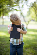 toddler boy hugging a Bible 
