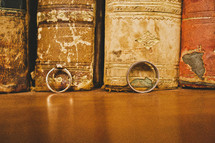 wedding band and engagement ring in front of old books