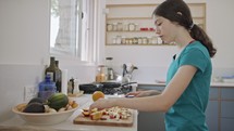 Teenage girl working cutting fruit for breakfast in the kitchen