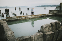 man and a woman standing behind water filled ruins