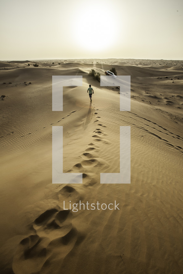 man running on sand dunes in a desert in Dubai