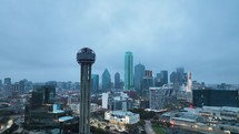 Reunion Tower in Dallas, Texas on a cloudy/gloomy morning with the skyline behind it.