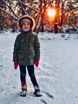 a little girl in a coat standing in snow 