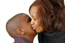 A mother and son sharing a kiss on the cheek.