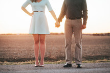 a couple holding hands outdoors at sunset 