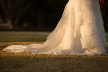 Train of a wedding gown on the grass in the daytime.