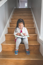 toddler girl reading a Bible on steps 