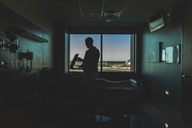 Silhouette of doctor talking to patient lying in hospital bed.