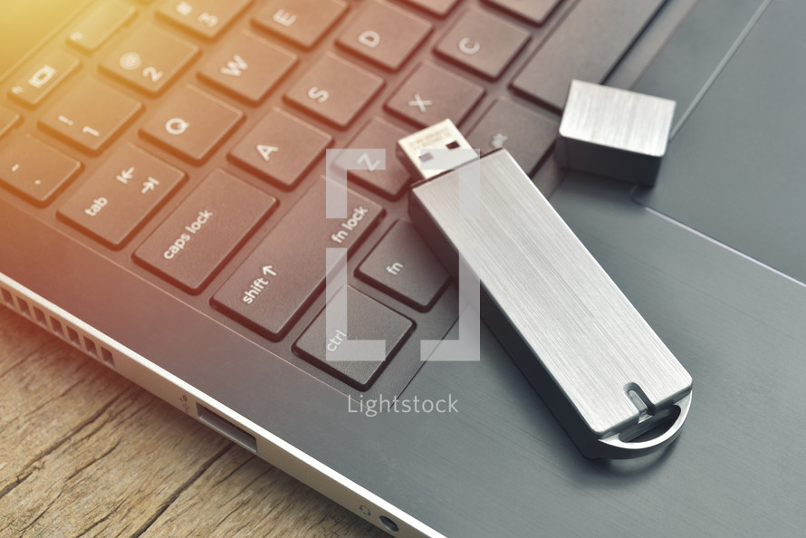 Close up of USB flash drive connected to laptop on wood desk