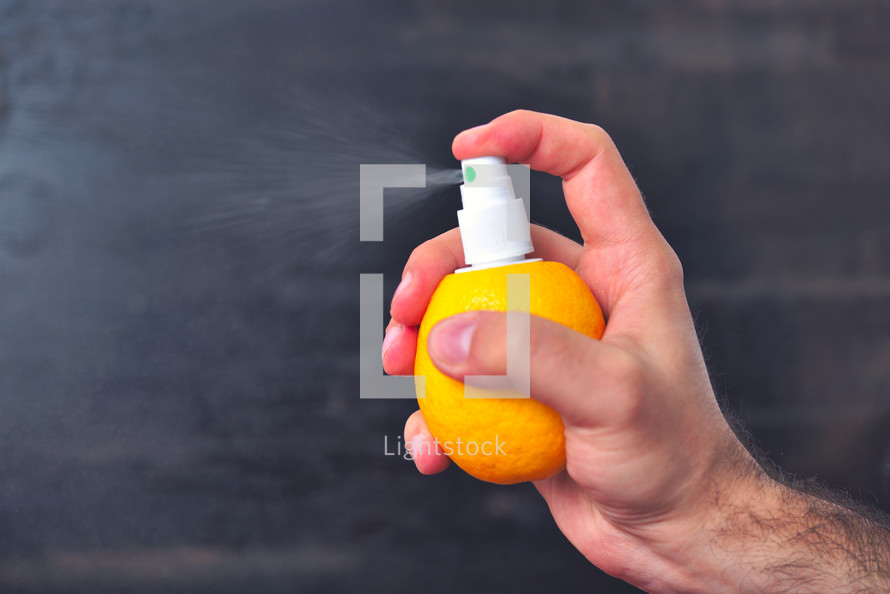 Man sprinkles juice from lemon with help of pump for spray. Healthy food and vitamins. Lemon juice spray concept
