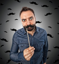 Young man with photo booth shaped mustache and background with small mustaches