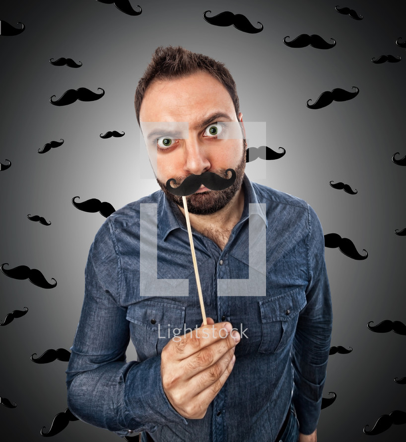 Young man with photo booth shaped mustache and background with small mustaches