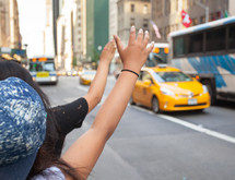 Tourists call a yellow cab in Manhattan with typical gesture with arm up