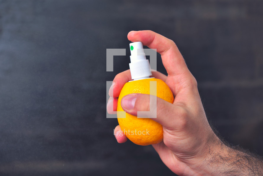 Man sprinkles juice from lemon with help of pump for spray.