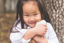 a girl child hugging her stuffed animal 