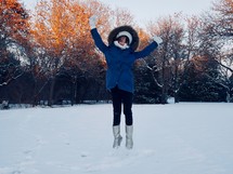 a girl jumping in snow 