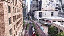 A drone pans out from an old building, revealing Main Street with a metro link, transit train in downtown Houston, Texas.