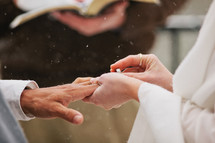 bride putting a ring on her grooms finger in the snow