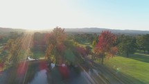 aerial view over a golf course and pond in fall 