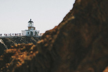 A lighthouse beyond a rocky cliff.