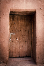 wooden door to a clay building 