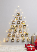 24 Gifts Calendar Hanging on Wall with Twinkling Christmas Lights and gifts on the floor