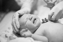 Nurse listening to the heartbeat of a newborn baby.