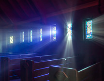 rays of sunlight shining through stained glass windows in onto church pews 