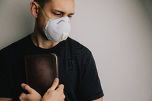 man in a N95 mask  holding a Bible 