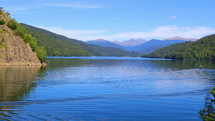 Beautiful panorama with lake in the mountains and boat on water and blue sky. Touristic and travelling destination. Hand held