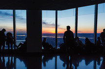 people sitting in windows looking out at the NYC skyline at sunset 