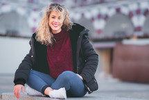 curly haired blonde woman sitting on bench. Casual clothes