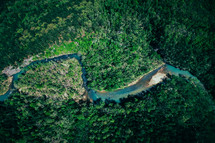 aerial view over a river winding through a forest 