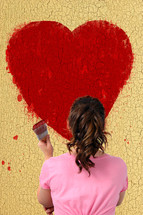 woman painting a red heart 