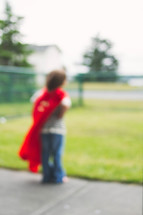 blurry image of a boy child in a cape 