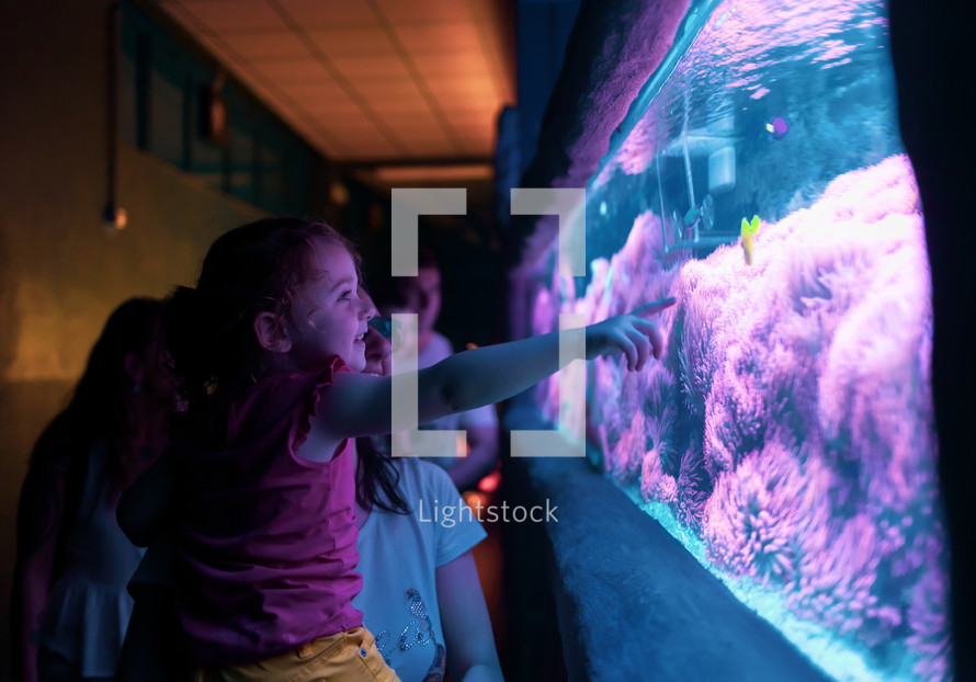 Happy family looking at fish tank at the aquarium.