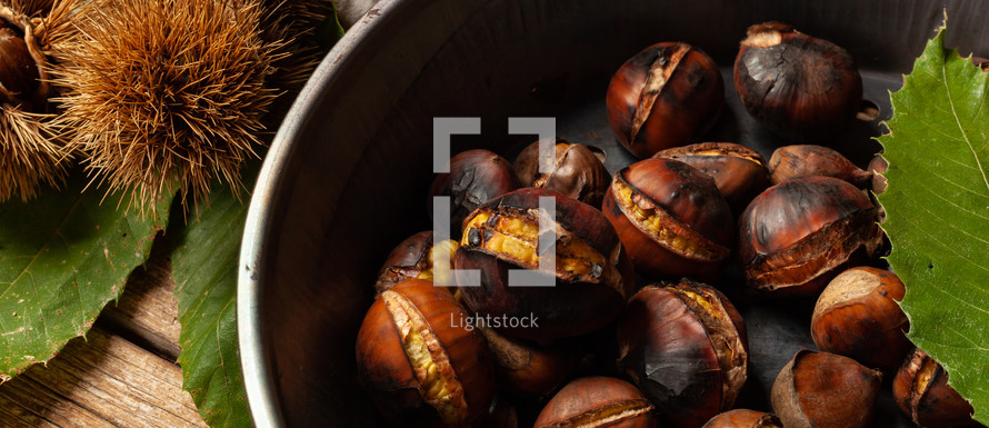 Roasted chestnuts in iron skillet on wooden table