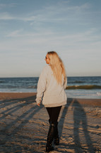 a woman walking on a beach in boots 