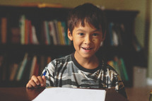 A smiling boy doing his homework