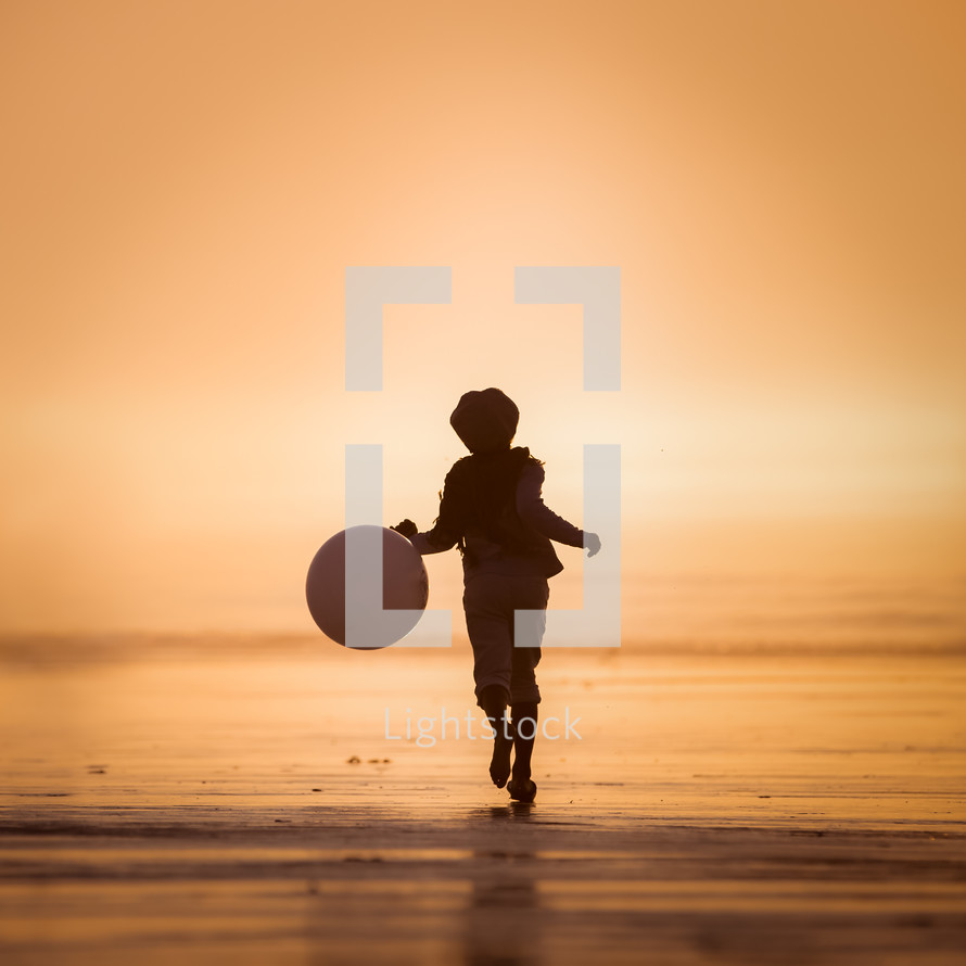 a child running with a ball on a beach 