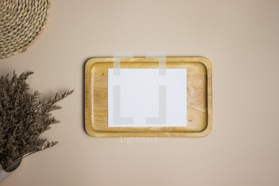 Blank white note on wooden plate with dried flowers